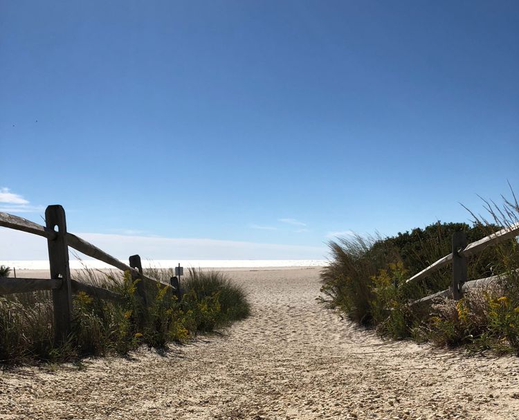 The image is of a sandy path to the beach.